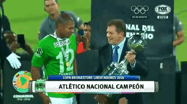 a man holding a trophy with the word atletico on it