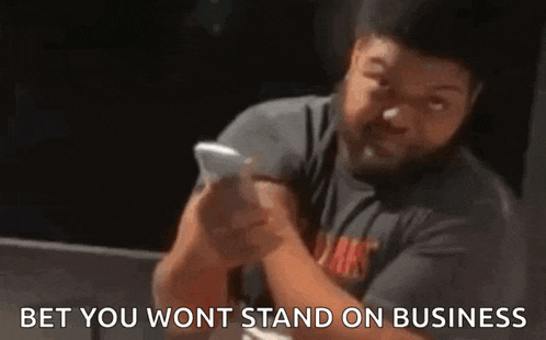 a man with a beard is holding a cell phone in his hand .