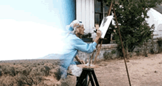 a woman is painting a picture on an easel