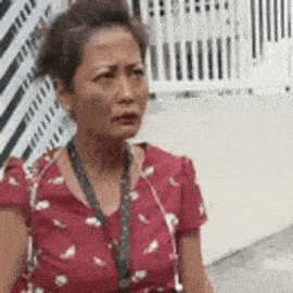 a woman in a red dress is sitting on the sidewalk looking at the camera .