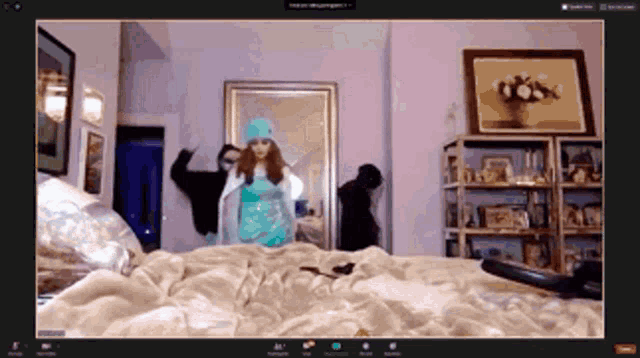 a woman in a blue hat is dancing in front of a mirror on a zoom call