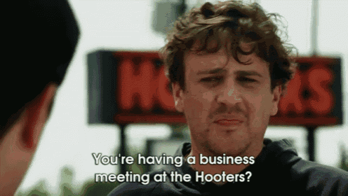 a man in front of a hooters sign asks if he 's having a business meeting