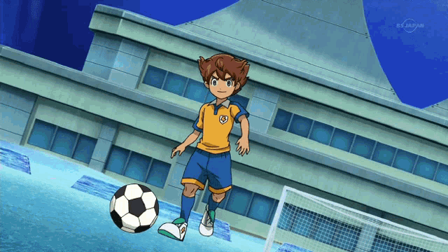 a boy is kicking a soccer ball in front of a building that says tv asahi