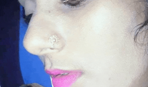 a close up of a woman 's face with a nose ring and pink lips .