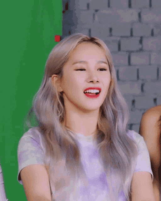 a woman with blonde hair is smiling in front of a green screen