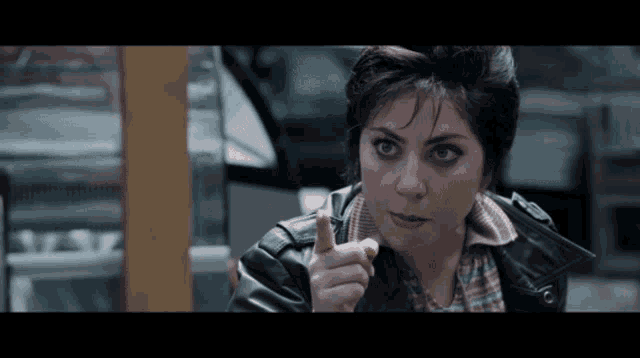 a woman wearing a leather jacket is pointing at something