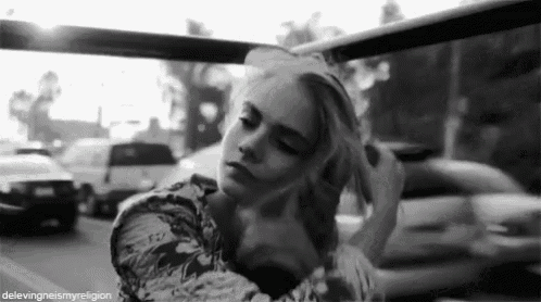 a black and white photo of a woman sitting in a car .
