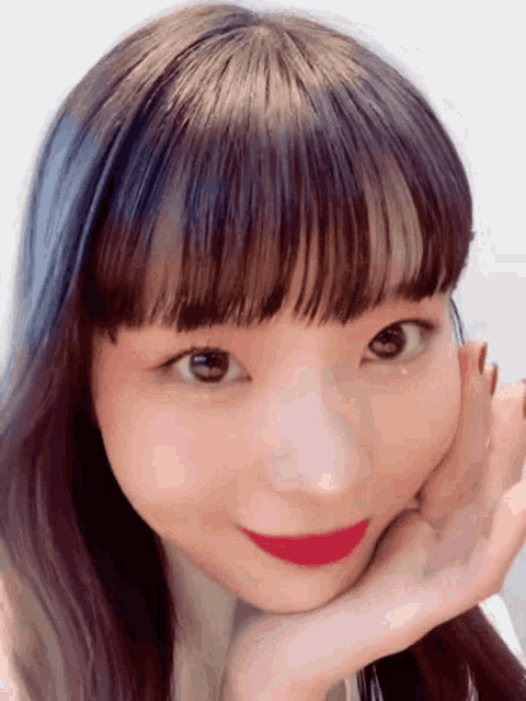 a close up of a girl 's face with her hand on her chin