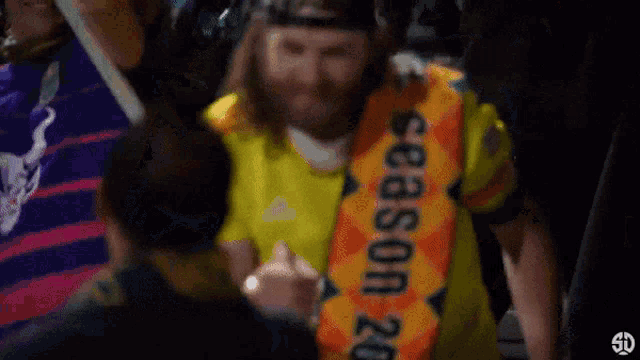 a man with a beard wearing a yellow shirt that says season