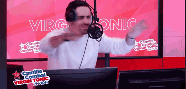 a man wearing headphones stands in front of a microphone with the words virgin tonic behind him