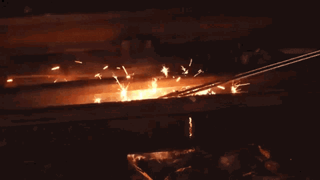 a bunch of people are standing in a dark room with a fire coming out of the ceiling