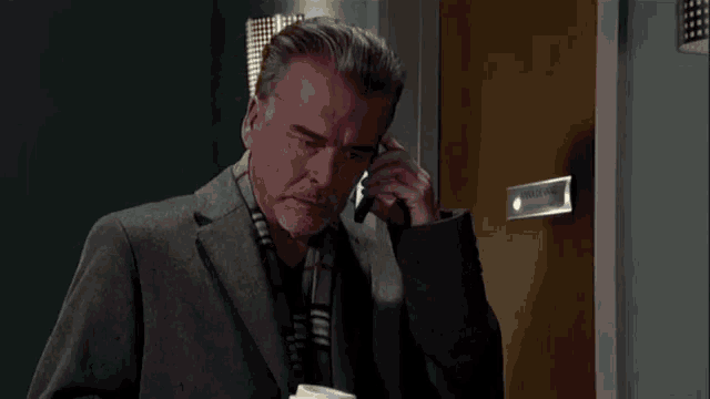 a man in a suit and tie stands in a doorway holding a cup of coffee