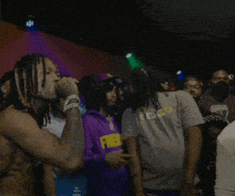 a man with dreadlocks is singing into a microphone in front of a crowd wearing a t-shirt that says kenzo