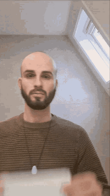a bald man with a beard wearing a striped shirt