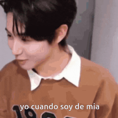 a young man wearing a brown sweater and a white collar is talking in spanish .