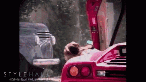 a woman is sitting in a pink sports car with the hood open