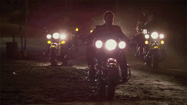 a man is riding a motorcycle at night with a glowing headlight