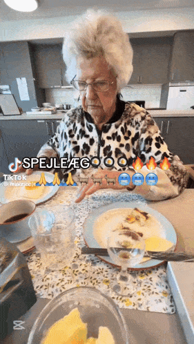an older woman is sitting at a table with a plate of food and a glass of wine
