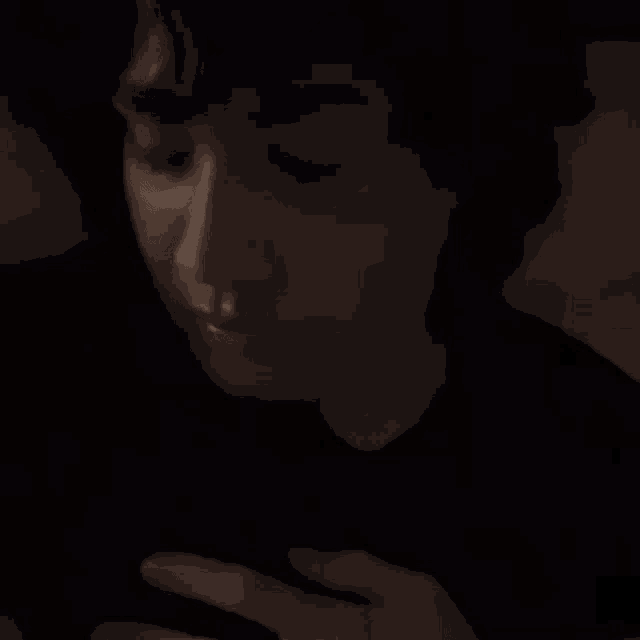 a close up of a person 's face in the dark looking at their phone .