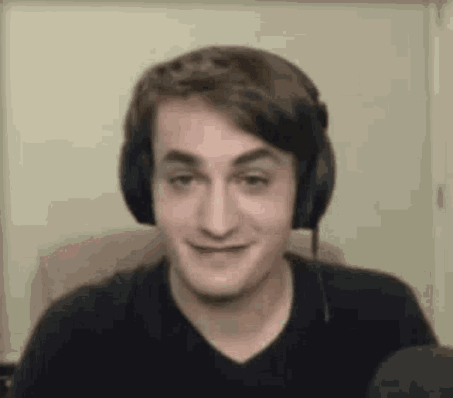 a man wearing headphones is making a funny face while sitting in front of a microphone .