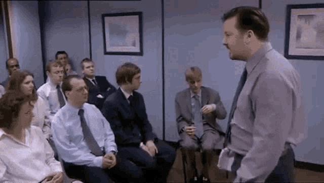 a man is standing in front of a group of people sitting in chairs in a room .