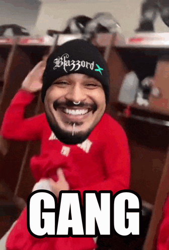 a man wearing a beanie and a red shirt with the word gang written on it