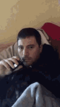 a man is smoking an electronic cigarette while laying in bed .