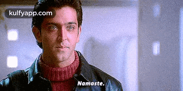 a man is wearing a leather jacket and a red sweater and says namaste .