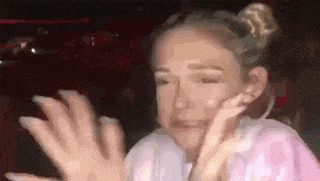 a woman is making a funny face while waving her hands in the air .