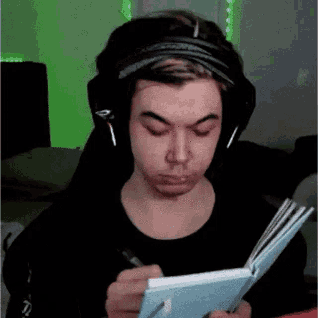 a man wearing headphones is writing in a notebook while sitting in a chair .