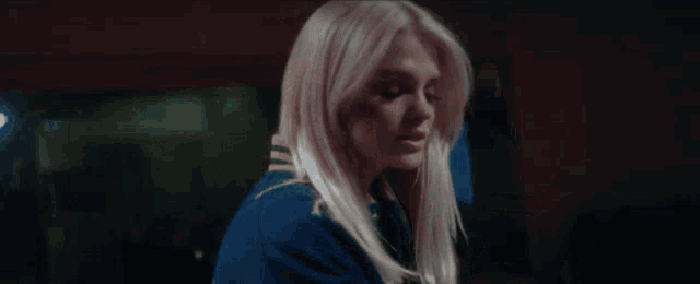 a woman with blonde hair is wearing a blue jacket