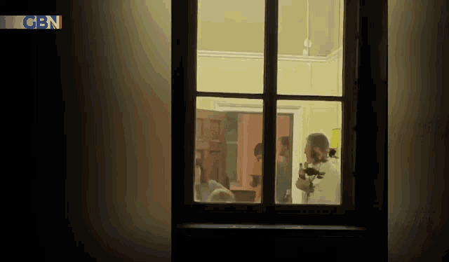 a group of people are standing in a room behind a window with cn on the bottom