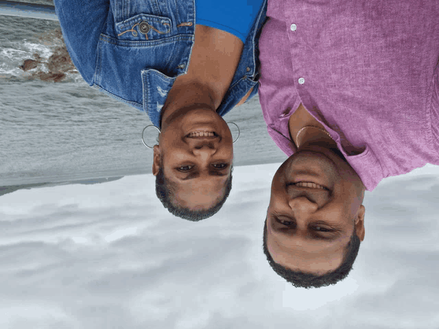 a man and a woman are standing upside down and smiling at the camera
