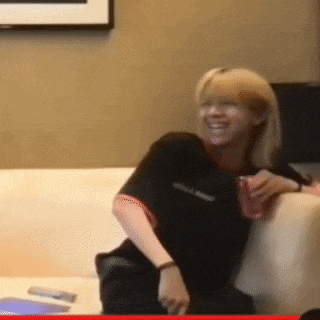 a woman is sitting on a couch and smiling while holding a cup .