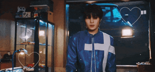 a man in a blue jacket is standing in front of a window with a heart drawn on it and the word com written on it