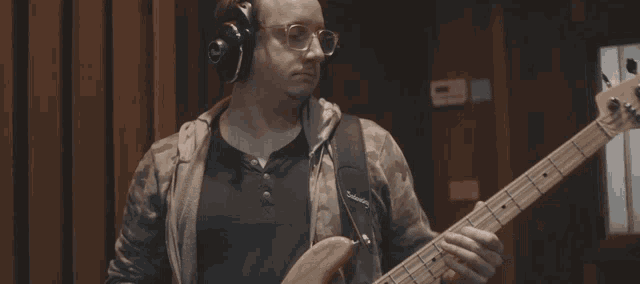 a man wearing headphones is playing a guitar with a strap that says ' fender ' on it