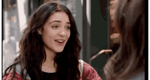 a young woman is smiling while talking to another woman on the street .