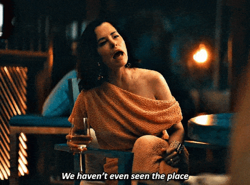 a woman is sitting in a chair holding a glass of wine and says we haven 't even seen the place