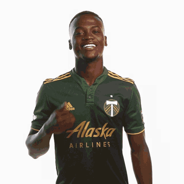 a man in a green alaska airlines shirt gives a thumbs up