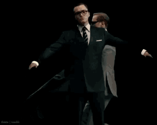 two men in suits are standing next to each other in front of a fire .