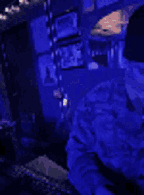 a man is smoking a cigarette in a dark room with a blue light behind him .