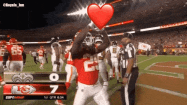 a football player is holding a heart in front of his face while standing on the field .