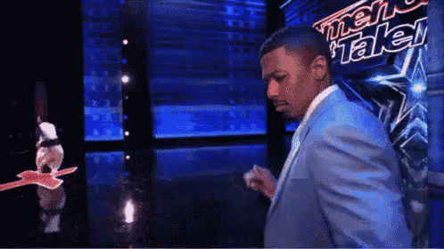 a man in a blue suit is standing in front of a sign that says america 's got talent