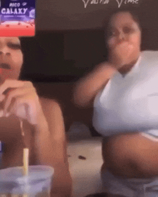 two women are sitting next to each other in front of a screen that says galaxy on it .