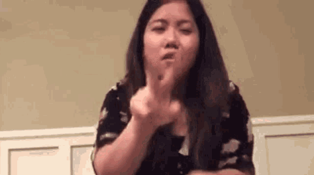 a woman is making a rude gesture with her finger .