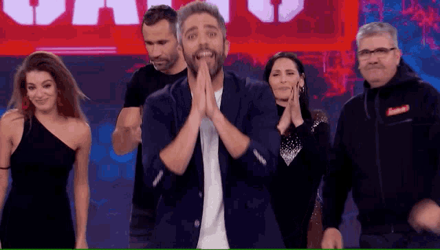 a group of people are clapping and dancing in front of a sign that says ' supreme ' on it .