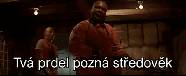 two men are standing next to each other in a dark room with a foreign language written on the bottom of the screen .