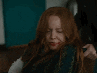 a woman with red hair and blood on her face is holding a knife