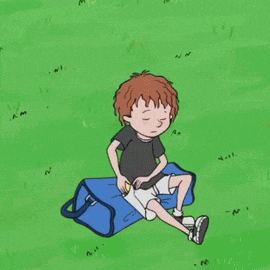 a boy is sitting on a blue bag in the grass