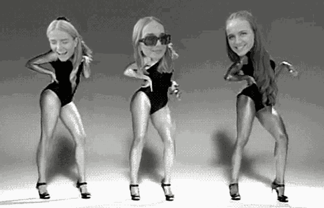 a black and white photo of three women in swimsuits dancing